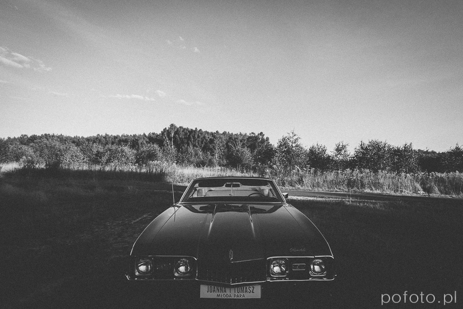 czarno białe zdjęcie opuszczonego Oldsmobila na polanie