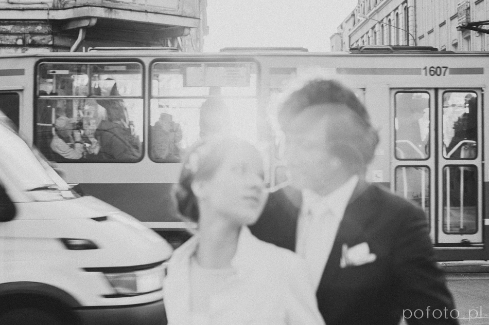 czarno białe zdjęcie młodej pary poza głębią ostrości, w tle zgiełk miasta